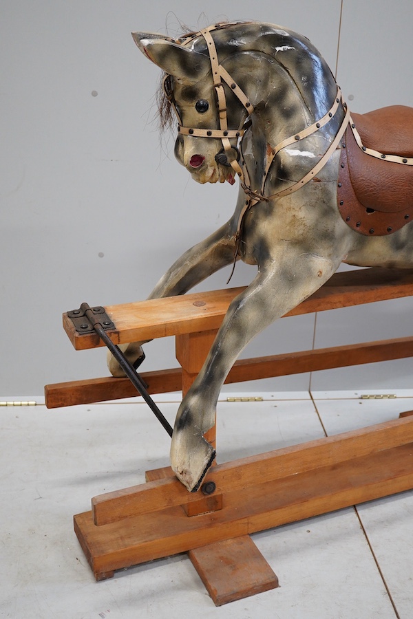 An early 20th century dapple grey rocking horse, on later trestle base, length 132cm. Condition - fair.